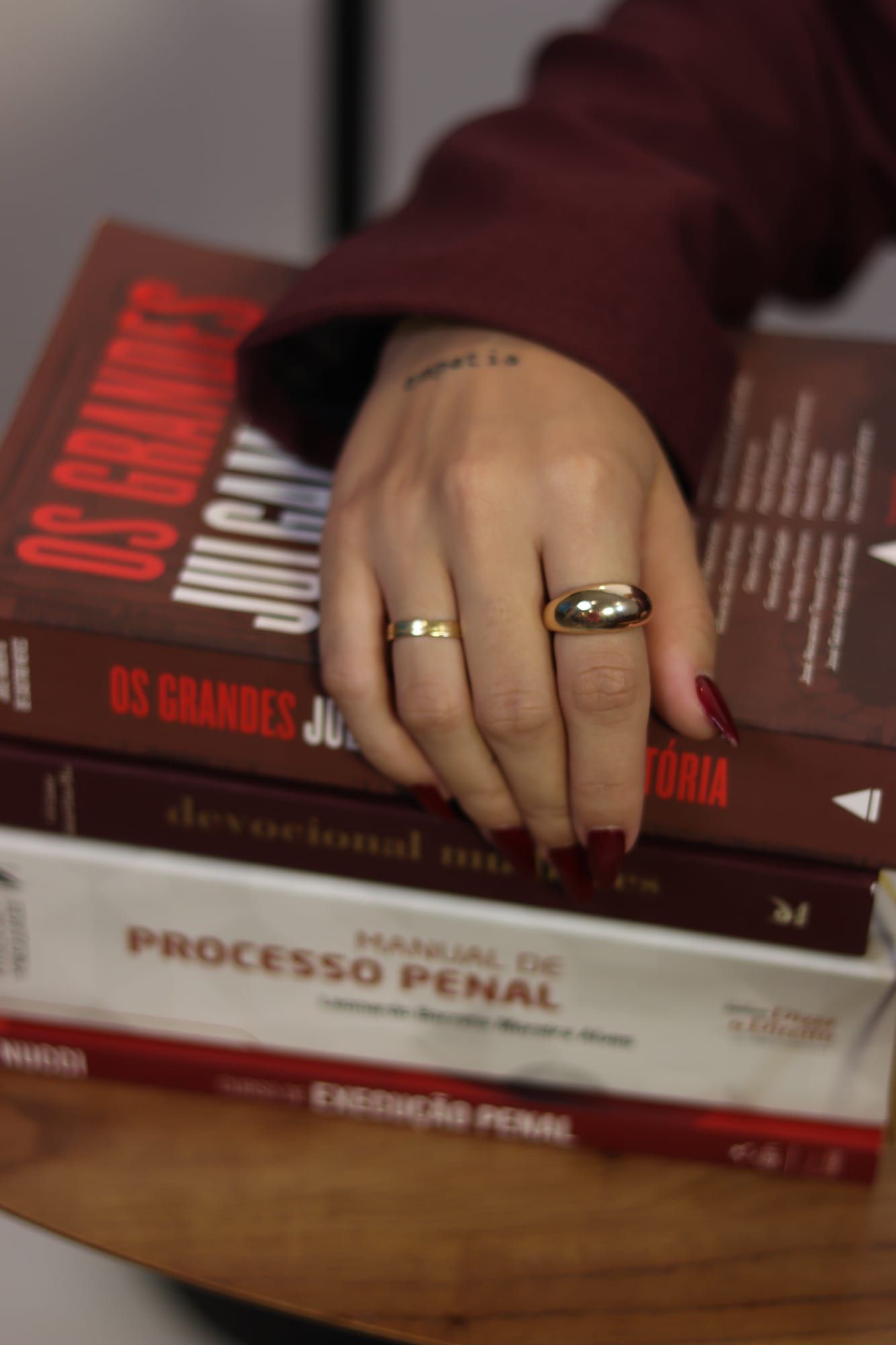 Mão de Danielle Machado apoiada sobre os livros de direito criminal